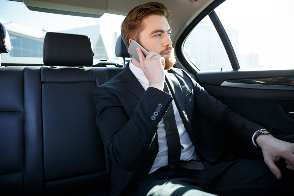 confident bearded businessman talking on a mobile phone when renting Business luxury transportation service.